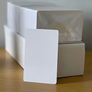 Bulk packaging of blank white PVC cards showing 100-card pack with protective wrapping, CR80 size 86x54mm